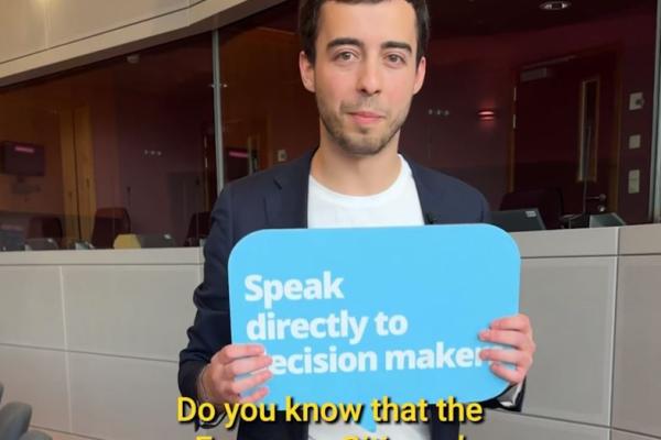 Young man holding a sign that reads 'Speak directly to decision makers'